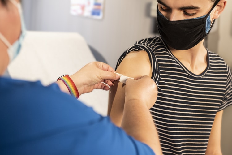A healthcare worker is placing a bandage on a woman after receiving her vaccine, taken February 2, 2021. 
