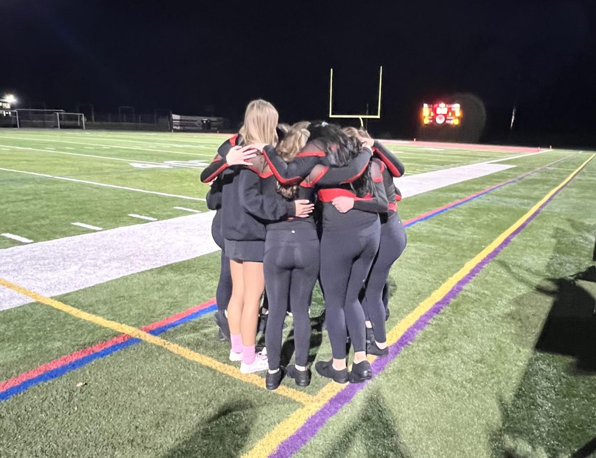 Varsity dance team has one final group hug after senior dancers perform at their last football game on Oct. 13.