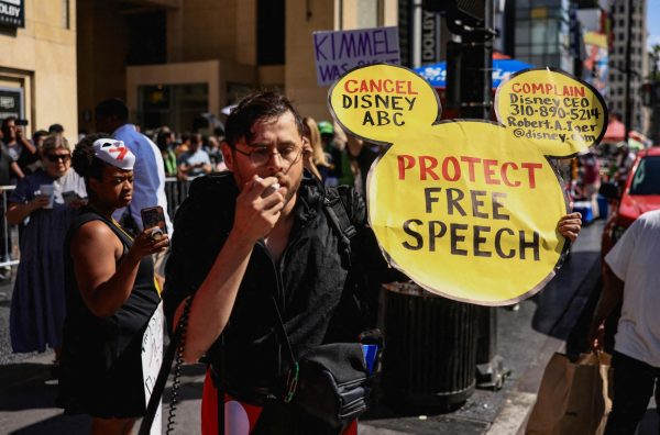 A man holds a sign in the shape of Mickey Mouse's face during a protest outside the Dolby Theatre, across the street from the theater where "Jimmy Kimmel Live!" was recorded for broadcast, following his suspension for remarks he made regarding Charlie Kirk’s assassination, on Hollywood Boulevard in Los Angeles, California, U.S. September 22, 2025. REUTERS/David Swanson