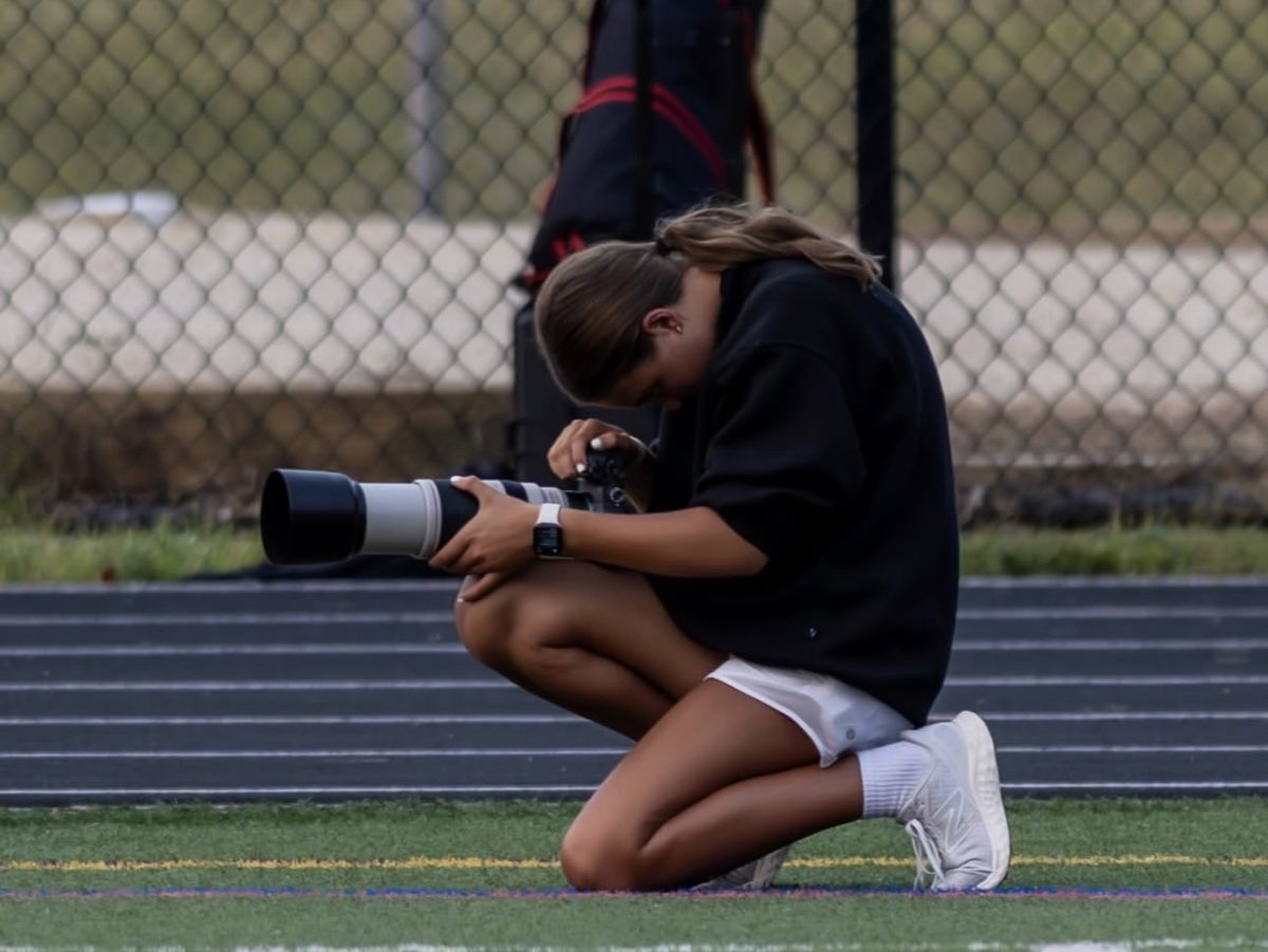 Sophomore Skylar Lacerda shown on the sidelines of a game with her camera. 