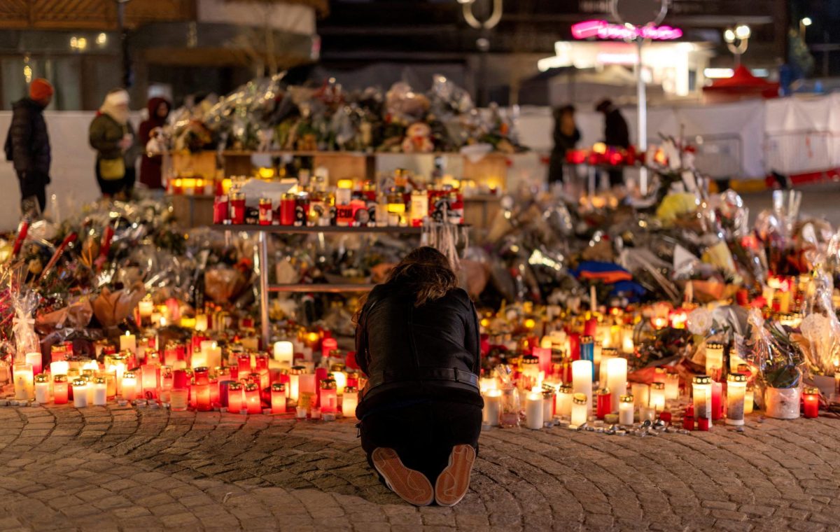A woman lights a candle at a makeshift memorial outside the "Le Constellation" bar, after a deadly fire and explosion during a New Year's Eve party, in the upscale ski resort of Crans-Montana in southwestern Switzerland, January 5, 2026. REUTERS/Umit Bektas