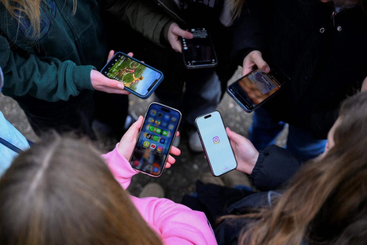 Teenagers pose for a picture while looking at their phones, in Bonn, Germany, February 20, 2026. REUTERS/Jana Rodenbusch