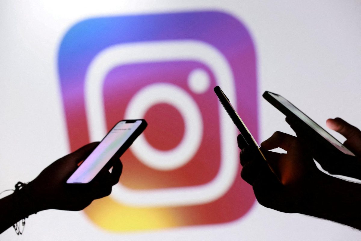 Teenagers pose for a photo while holding smartphones in front of a Facebook logo in this illustration taken September 11, 2025. REUTERS/Dado Ruvic/Illustration